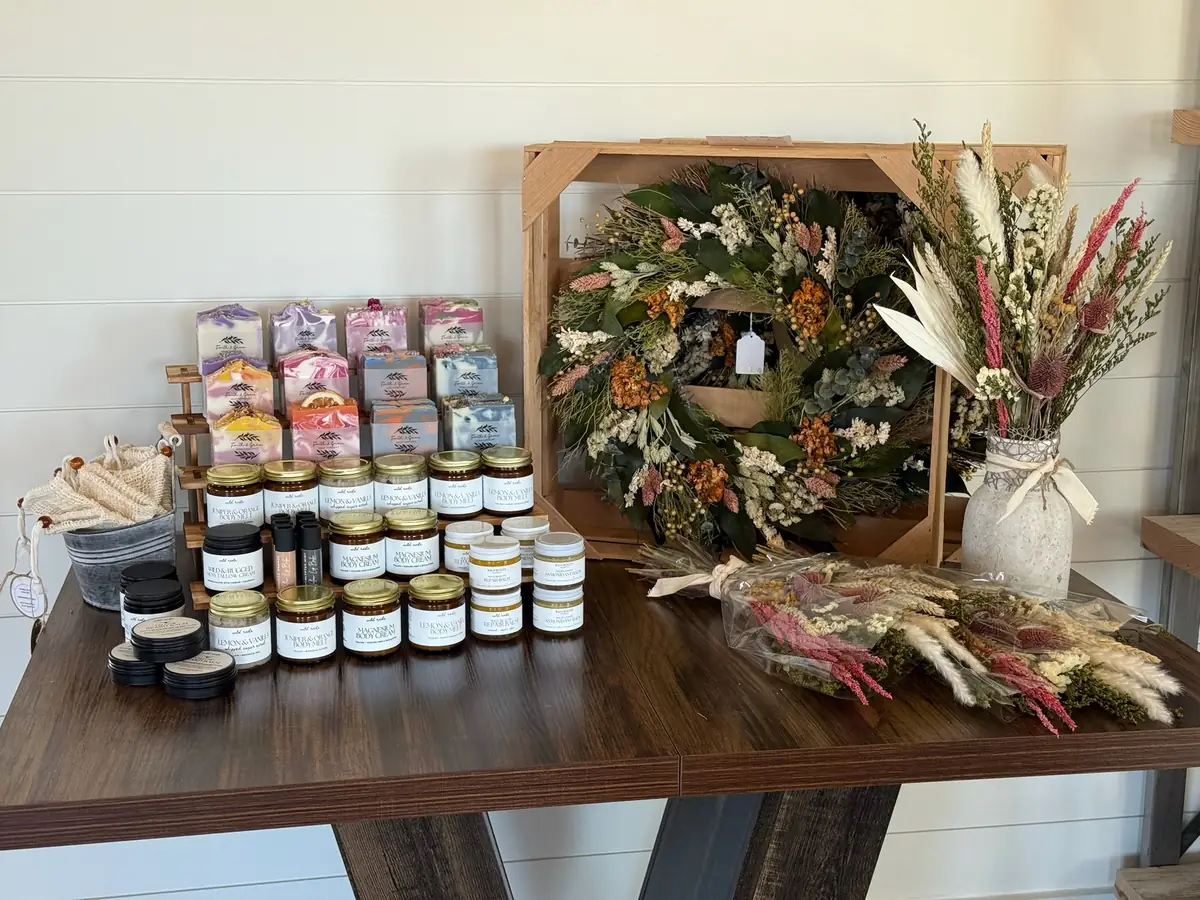 A boutique table with jarred candles, a dried-flower wreath and dried bouquets